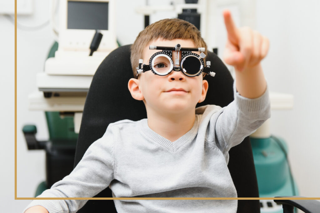 A young child wearing optometric trial frames while holding up fingers in front of them, participating in a vision test during an eye exam.